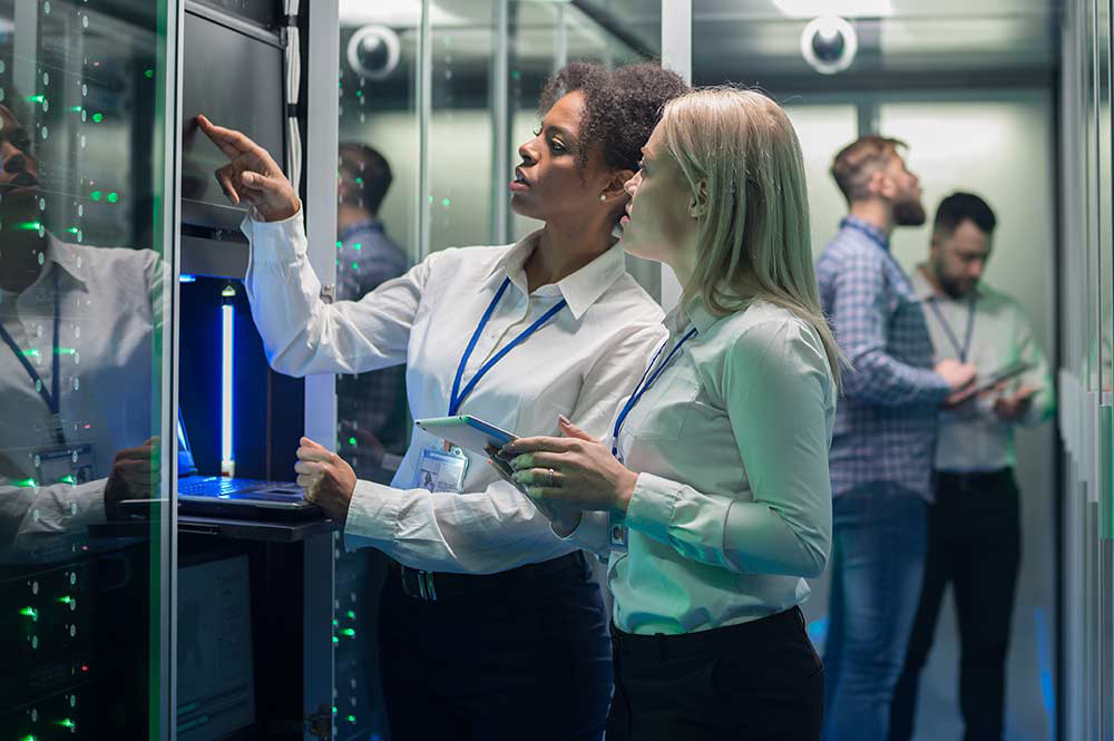 Two people looking at screen next to servers